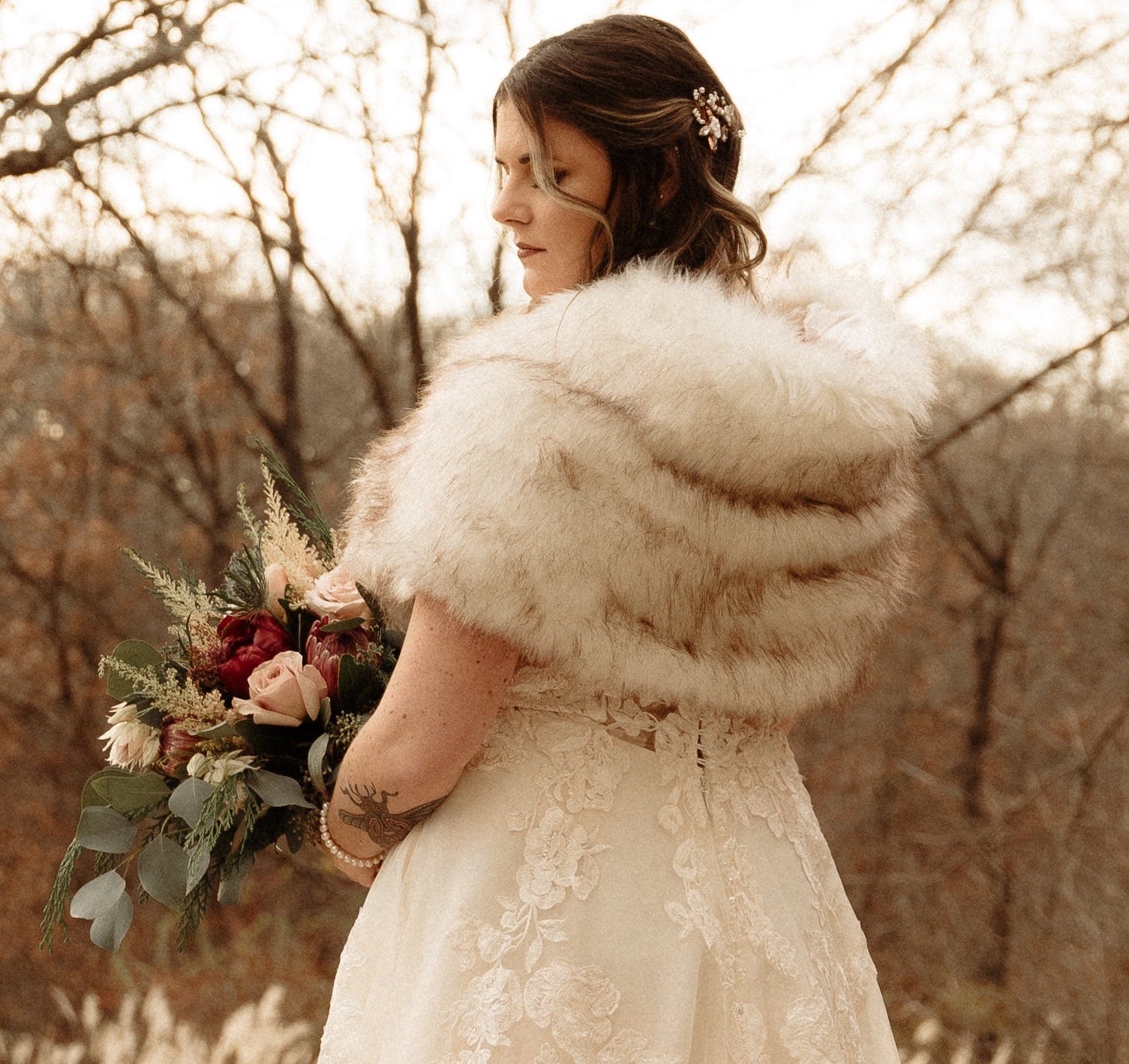 winter wedding photo of bride in wedding dress with shawl and wedding flower bouquet