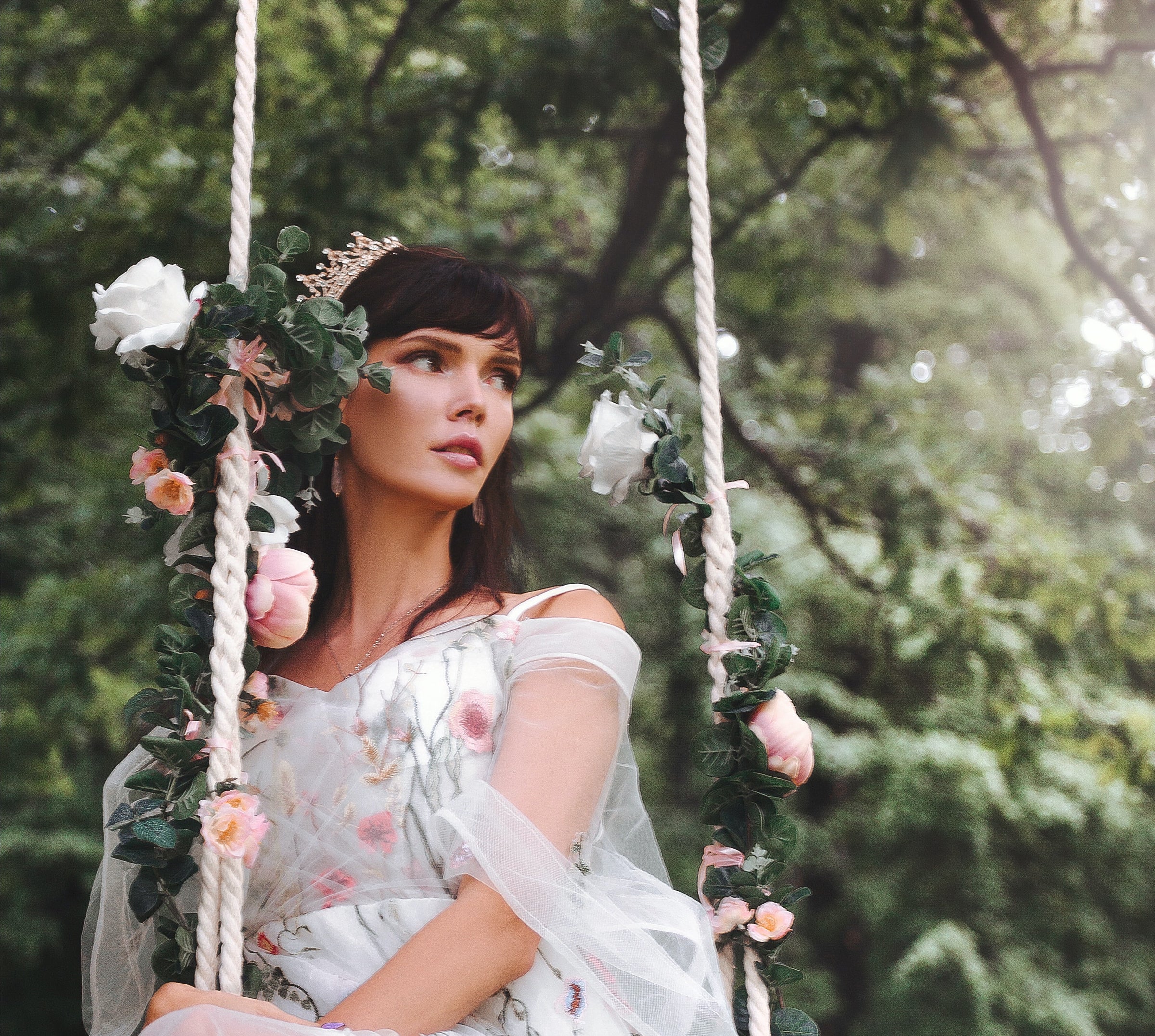 Whimsical wedding photo of bride on floral rope swing