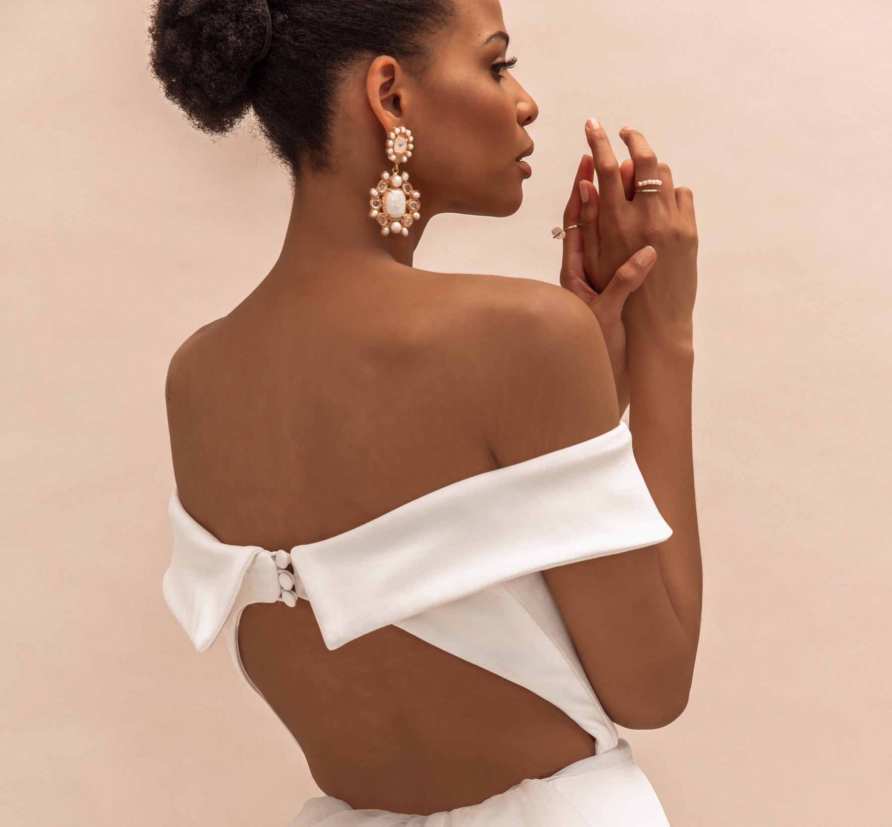 Profile of woman in white dress showcasing her jewelry